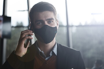 Image showing business man wearing coronavirus medical face mask while using smartphone