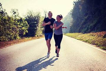 Image showing young couple jogging along a country road