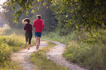 Image showing young couple jogging along a country road