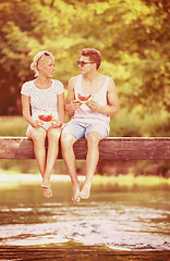 Image showing couple enjoying watermelon while sitting on the wooden bridge