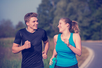 Image showing young couple jogging along a country road