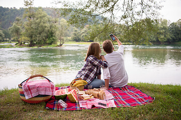 Image showing Couple taking a selfie by mobile phone while enjoying picnic tim