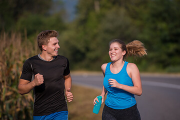 Image showing young couple jogging along a country road