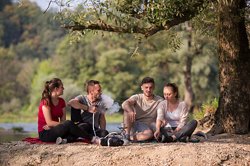 Image showing friends smoking hookah on the river bank