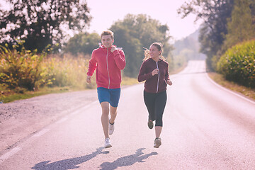 Image showing young couple jogging along a country road