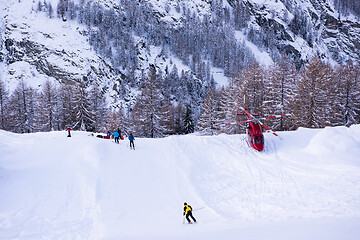 Image showing rescue team with a red helicopter rescuing a hurt skier