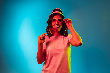 Image showing Happy young woman standing and smiling against blue background