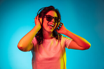 Image showing Happy young woman standing and smiling against blue background