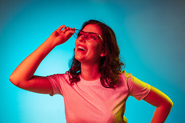 Image showing Happy young woman standing and smiling against blue background