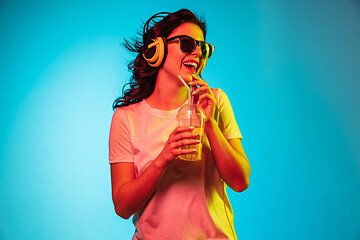 Image showing Happy young woman standing and smiling against blue background