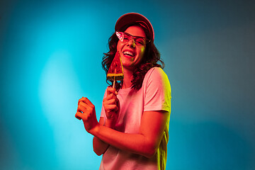 Image showing Happy young woman standing and smiling against blue background