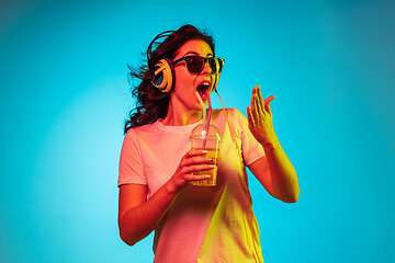 Image showing Happy young woman standing and smiling against blue background