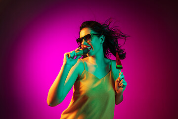 Image showing Happy young woman standing and smiling against pink background