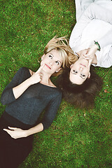 Image showing Two thoughtful girls lying in the grass