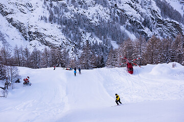 Image showing rescue team with a red helicopter rescuing a hurt skier