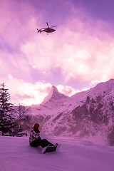 Image showing rescue team with a red helicopter rescuing a hurt skier