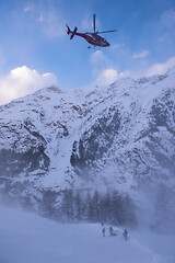 Image showing rescue team with a red helicopter rescuing a hurt skier