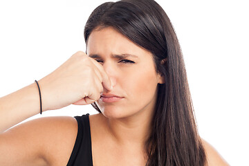 Image showing portrait of a brunette woman pinching her nose because of a bad 