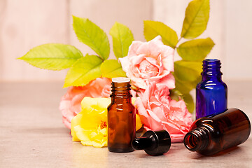 Image showing rose flowers and bottles of essential oils for aromatherapy