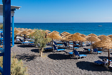 Image showing beach with umbrellas and deck chairs by the sea in Santorini