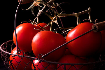 Image showing big red tomatoes on black background in light dark ready to cook