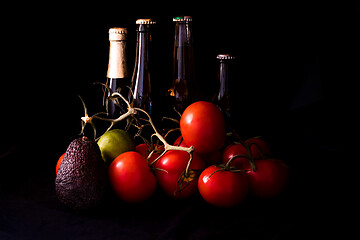 Image showing large red and ripe tomatoes with lime avocado and bottle of beer