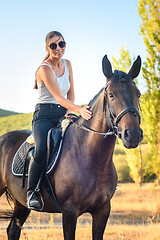 Image showing Beautiful slender pretty girl sitting on a horse, close-up
