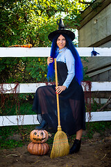 Image showing Cute girl in a witch costume with pumpkins and a broom at a Halloween party