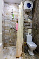 Image showing Small compact bathroom divided with shower curtain and toilet