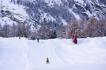 Image showing rescue team with a red helicopter rescuing a hurt skier