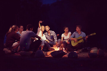 Image showing young friends relaxing around campfire