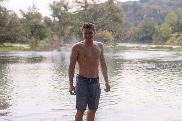 Image showing man with a bare torso splashing water