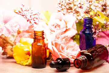 Image showing rose flowers and bottles of essential oils for aromatherapy