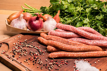 Image showing raw sausages with chilli and herbs on a wooden board with spices