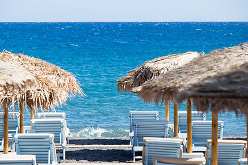 Image showing beach with umbrellas and deck chairs by the sea in Santorini