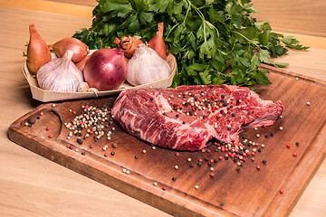 Image showing steak of beef on a wooden board with spices pepper parsley salt 