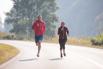 Image showing young couple jogging along a country road