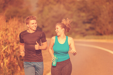 Image showing young couple jogging along a country road