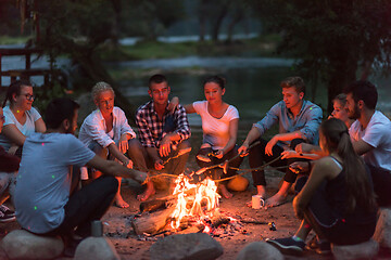 Image showing young friends relaxing around campfire