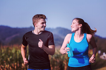 Image showing young couple jogging along a country road