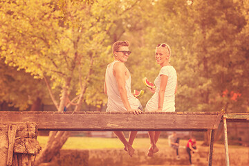 Image showing couple enjoying watermelon while sitting on the wooden bridge