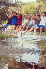 Image showing friends enjoying watermelon while sitting on the wooden bridge