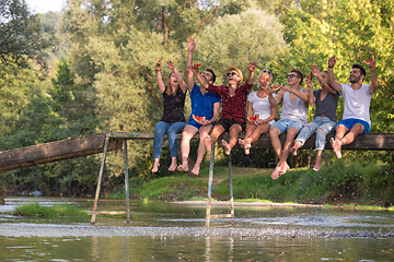 Image showing friends enjoying watermelon while sitting on the wooden bridge