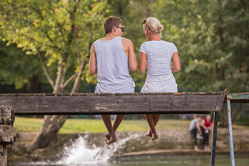 Image showing couple enjoying watermelon while sitting on the wooden bridge