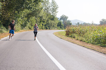 Image showing young couple jogging along a country road