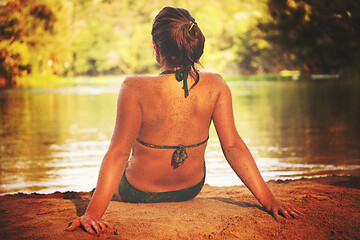 Image showing girl in a green bikini relaxing on the riverbank