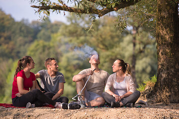 Image showing friends smoking hookah on the river bank