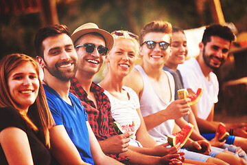 Image showing friends enjoying watermelon while sitting on the wooden bridge