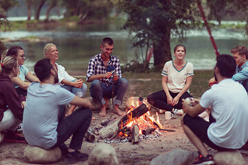 Image showing young friends relaxing around campfire