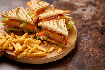 Image showing Club sandwiches served on a wooden board. With hot French fries